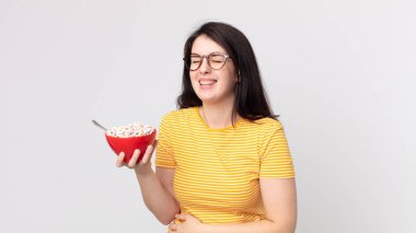 Güzel bir kadın komik bir şakaya kahkaha atıyor ve elinde kahvaltı kasesi tutuyor.