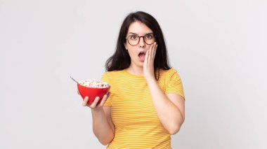 Güzel bir kadın şok olmuş, korkmuş ve elinde bir kahvaltı kasesi tutuyor.