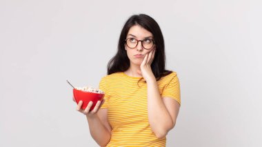 Güzel bir kadın sıkılmış, hayal kırıklığına uğramış ve uykulu hissediyor yorucu bir günün ardından elinde bir kahvaltı kasesi tutuyor.