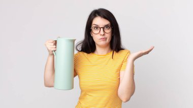 Güzel bir kadın şaşkın, şaşkın, şüpheci ve elinde kahve termosu tutuyor.