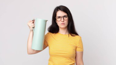 Güzel bir kadın üzgün, üzgün ya da kızgın ve yana bakıyor ve elinde kahve termosu tutuyor.