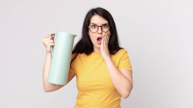Güzel bir kadın şoke olmuş, korkmuş ve elinde kahve termosu tutuyor.