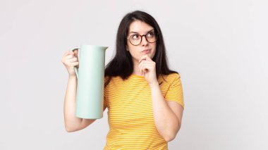 Düşünen, kuşkulu, kafası karışık ve elinde kahve termosu tutan güzel bir kadın.