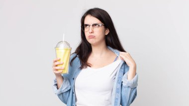 Güzel bir kadın stresli, endişeli, yorgun ve hayal kırıklığına uğramış ve elinde vanilyalı milkshake tutuyor.