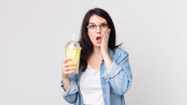 Güzel bir kadın şoke olmuş, korkmuş ve elinde vanilyalı milkshake tutuyor.