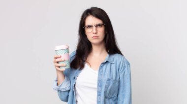 Güzel bir kadın üzgün, üzgün ya da kızgın ve yana bakıyor ve elinde kahve tutuyor.