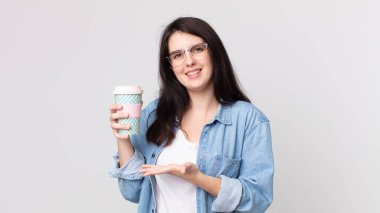 Güzel bir kadın neşeyle gülümsüyor, mutlu hissediyor ve bir konsept gösteriyor ve kahve alıp götürüyor.