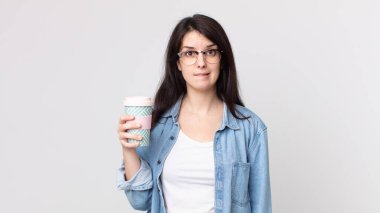 Kafası karışmış, kafası karışmış ve elinde kahve tutan güzel bir kadın.