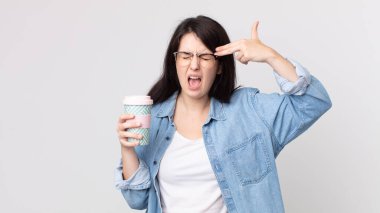 Güzel bir kadın mutsuz ve stresli görünüyor, intihar jesti silah işareti yapıyor ve elinde kahve tutuyor.
