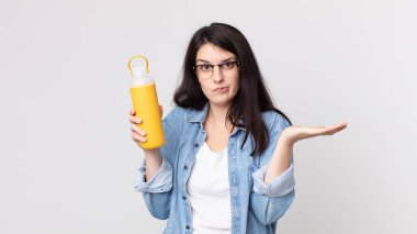 Güzel bir kadın şaşkın, şaşkın, şüpheci ve elinde kahve termosu tutuyor.