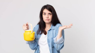 Güzel bir kadın şaşkın, şaşkın, şüpheci ve elinde çaydanlık tutan