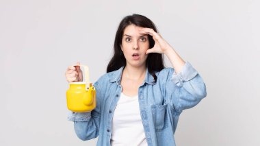 Güzel kadın mutlu, şaşkın ve şaşırmış görünüyor ve elinde bir çaydanlık tutuyor.