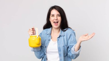 Güzel kadın kendini mutlu ve şaşkın hissediyor. İnanılmaz bir şey ve elinde bir çaydanlık tutuyor.