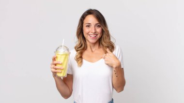 Oldukça zayıf bir kadın kendini mutlu hissediyor ve elinde vanilyalı milkshake ile kendini işaret ediyor.