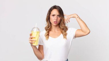 Kafası karışık ve kafası karışık bir kadın. Deli olduğunu ve elinde vanilyalı milkshake tuttuğunu gösteriyor.