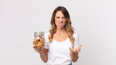 Oldukça zayıf bir kadın kızgın, sinirli ve hayal kırıklığına uğramış görünüyor ve elinde cam bir kurabiye şişesi tutuyor.