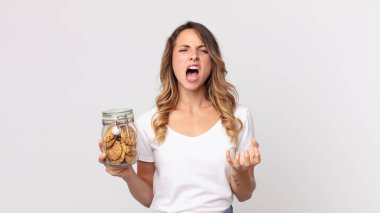 Oldukça zayıf bir kadın umutsuz görünüyor, hayal kırıklığına uğramış ve stresli ve elinde cam bir kurabiye şişesi tutuyor.