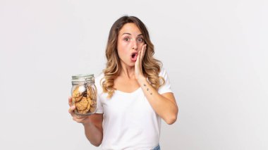 Oldukça zayıf bir kadın mutlu, heyecanlı ve şaşırmış hissediyor ve elinde bir kurabiye şişesi tutuyor.