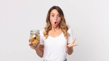 Oldukça zayıf bir kadın şok olmuş ve şaşırmış hissediyor ve elinde cam bir kurabiye şişesi tutuyor.