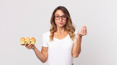 Oldukça zayıf bir kadın kapiş ya da para hareketi yapıyor. Sana ödemeni söylüyor ve elinde bir yumurta kutusu tutuyor.