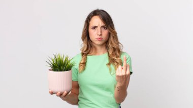 Oldukça zayıf bir kadın kızgın, sinirli, asi ve agresif ve elinde dekoratif bir bitki tutuyor.