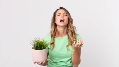 Oldukça zayıf bir kadın umutsuz görünüyor, hayal kırıklığına uğramış ve stresli ve elinde dekoratif bir bitki tutuyor.