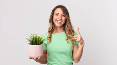 Bir fikri fark edip elinde dekoratif bir bitki tuttuktan sonra mutlu ve heyecanlı bir dahi gibi hisseden zayıf bir kadın.