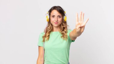 Oldukça zayıf bir kadın gülümsüyor ve arkadaş canlısı görünüyor. Dört numara kulaklıkla müzik dinliyor.