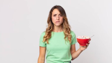 Kafası karışmış, kafası karışmış ve elinde kahvaltı kasesi tutan oldukça zayıf bir kadın.