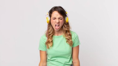 Oldukça zayıf bir kadın agresif bir şekilde bağırıyor, çok kızgın görünüyor kulaklıkla müzik dinliyor.