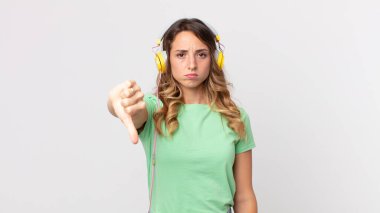 Oldukça zayıf bir kadın kendini kötü hissediyor, baş parmaklarını eğip kulaklıkla müzik dinliyor.