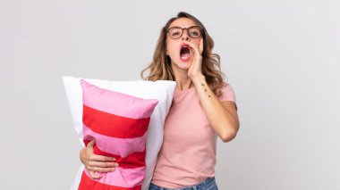 Oldukça zayıf bir kadın kendini mutlu hissediyordu. Elleri ağızının yanında pijama giymiş ve yastık tutuyordu.