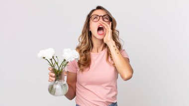 Oldukça zayıf bir kadın kendini mutlu hissediyordu. Elleri ağzının yanında ve elinde süslü çiçeklerle bağırıyordu.