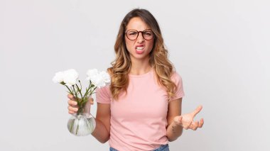 Oldukça zayıf bir kadın kızgın, sinirli ve hayal kırıklığına uğramış görünüyor ve elinde dekoratif çiçekler tutuyor.