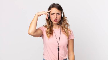 Kafası karışık ve kafası karışık olan zayıf bir kadın. Kulaklığı olan deli bir operatör asistanı olduğunu gösteriyor.