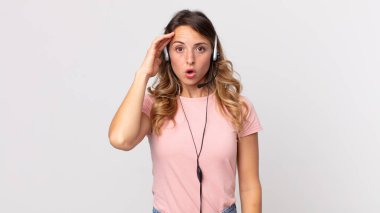 Oldukça zayıf bir kadın şaşırmış görünüyor, yeni bir düşünce, fikir ya da konsept fark ediyor. Kulaklığı olan bir operatör asistanı.