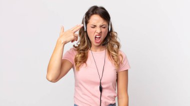 Oldukça zayıf bir kadın mutsuz ve stresli görünüyor, intihar jesti silah işareti yapıyor. Kulaklıklı bir operatör asistanı.