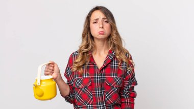 Oldukça zayıf bir kadın üzgün ve sızlanıyor mutsuz bir bakışla ve ağlıyor ve elinde çaydanlıkla