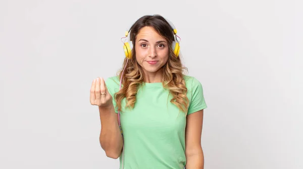 一个身材苗条的女人 用耳机让你支付听音乐的费用 — 图库照片