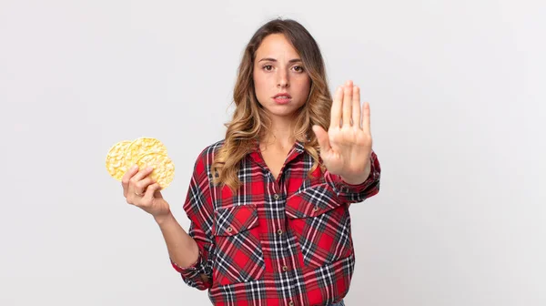 かなり薄い女性が真剣に見ていますオープンヤシ作りを停止ジェスチャーや食事療法の餅を保持します — ストック写真