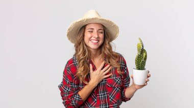 Oldukça zayıf bir kadın elinde kaktüs tutan komik bir şakaya yüksek sesle gülüyor. çiftçi kavramı