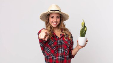 Oldukça zayıf bir kadın kamerayı işaret ederek seni kaktüs tutarak seçiyor. çiftçi kavramı