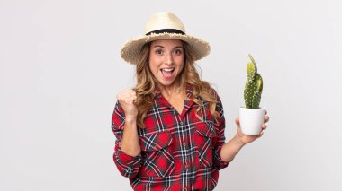 Oldukça zayıf bir kadın kendini şok olmuş hissediyor, gülüyor ve bir kaktüs tutarak başarıyı kutluyor. çiftçi kavramı