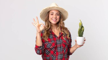 Oldukça zayıf bir kadın kendini mutlu hissediyor. Elinde kaktüs tutarken iyi bir jest yapıyor. çiftçi kavramı