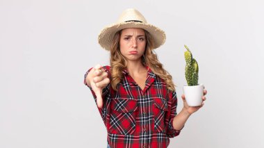 Kaktüs tutarken parmaklarını gösteren oldukça zayıf bir kadın. çiftçi kavramı