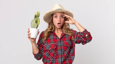 Oldukça zayıf bir kadın mutlu görünüyor, şaşırmış ve elinde bir kaktüs tutuyor. çiftçi kavramı