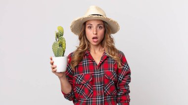 Oldukça zayıf bir kadın elinde kaktüs tutarken şok olmuş ya da şaşırmış görünüyor. çiftçi kavramı