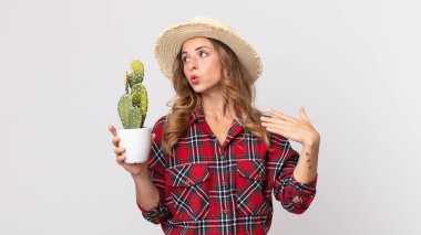 Stresli, endişeli, yorgun ve hayal kırıklığına uğramış bir kadın elinde kaktüs tutuyor. çiftçi kavramı