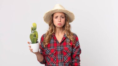 Oldukça zayıf bir kadın üzgün ve mızmızlanıyor. Mutsuz bir bakışı var ve elinde kaktüsle ağlıyor. çiftçi kavramı