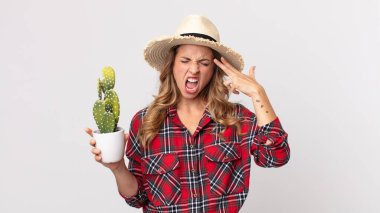 Oldukça zayıf bir kadın mutsuz ve stresli görünüyor, intihar jesti elinde kaktüs tutan bir silah işareti yapıyor. çiftçi kavramı